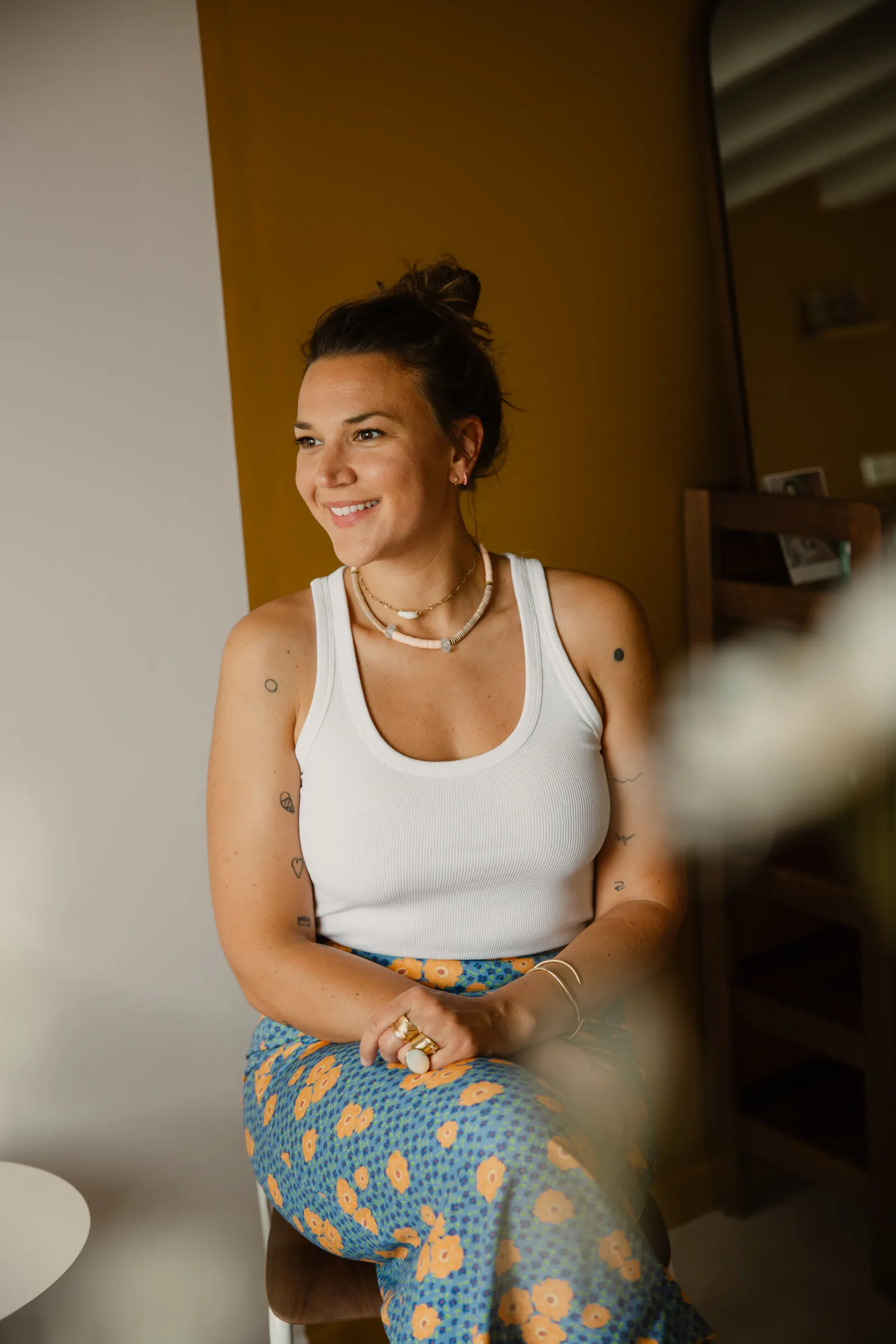Jeanne Lozay assise, débardeur blanc et jupe fleurie, sourire franc